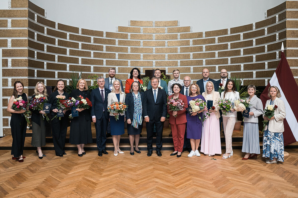 LU 2026. gada darbinieku sapulcē godinātie kolēģi ar ziediem un apbalvojumiem kopā ar universitātes vadību