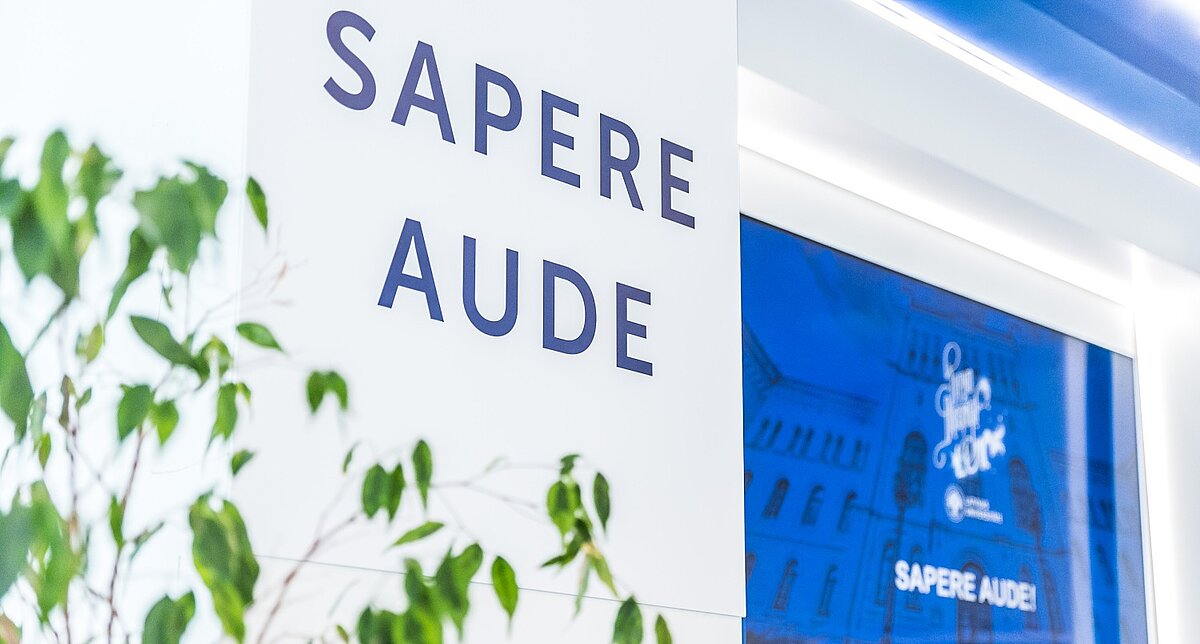 Latvijas Universitātes devīze “Sapere aude” uz sienas LU telpās.