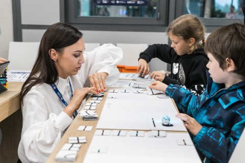 Bērni kopā ar LU IZPF pārstāvi piedalās izglītojošā galda aktivitātē.