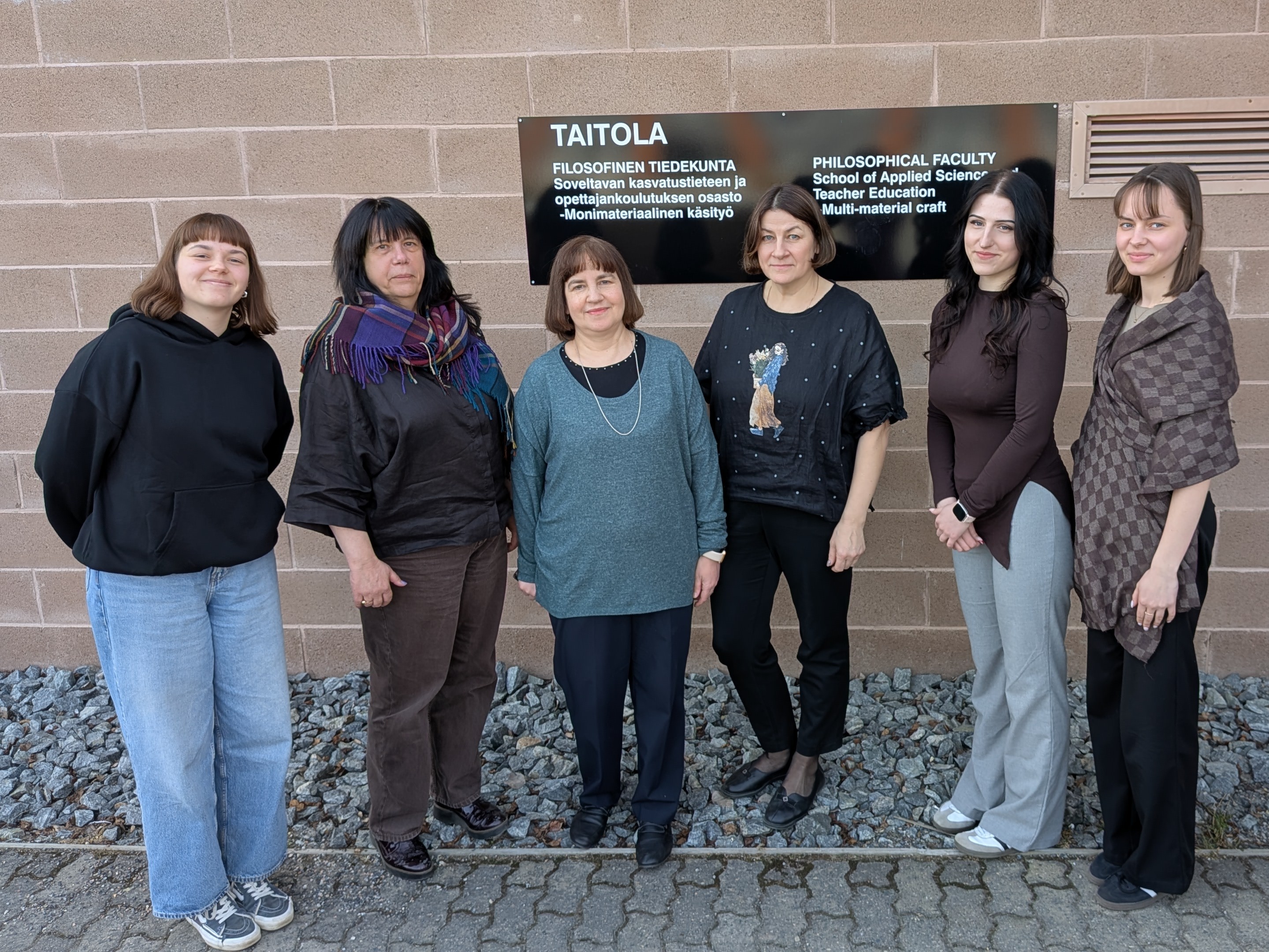 IZPF delegācija pie Austrumsomijas Universitātes Filosofijas fakultātes sienas. Uz sienas plāksne ar iestādes nosaukums